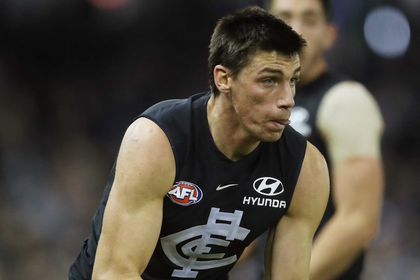 A Carlton AFL player holds the ball in both hands against Fremantle.