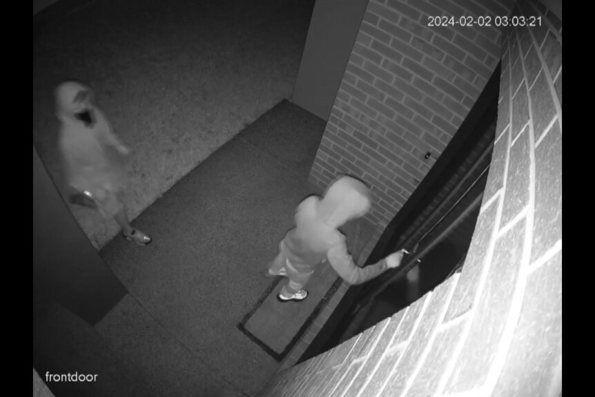 photo of camera vision shows someone checking to see if front door is open, second person with covered face in shot