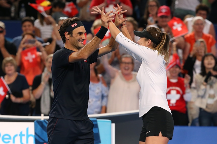 Roger Federer and Belinda Bencic high five after winning the Hopman Cup tennis tournament.