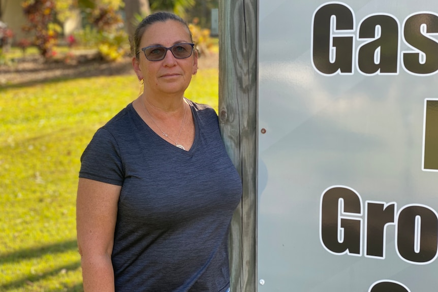 A middle-aged lady standing next to a caravan park sign