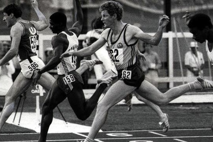 Une image en noir et blanc de Paul Narracott penché au-dessus de la ligne d'arrivée d'une course à pied.