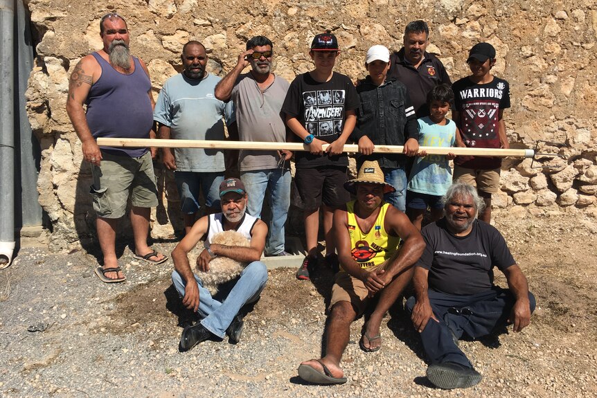 A group of First Nations people standing with a traditional three-pong harpoon used to catch Gynburra 