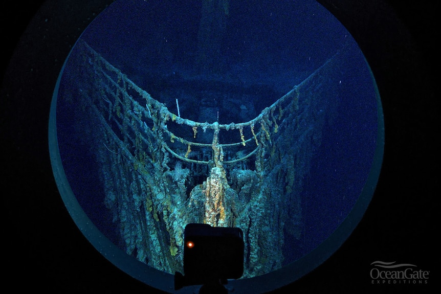 The bow of the wreckage of the Titanic, underwater, seen through a round porthole