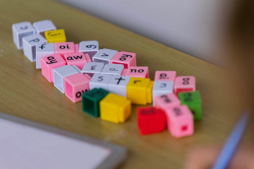 A group of colourful cubes with phonics written on them sit on a table.