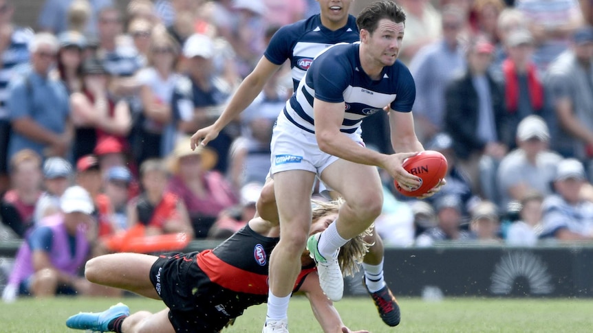 Patrick Dangerfield of the Cats beats a tackle by Essendon's Dyson Heppell in Colac on March 11, 2018.