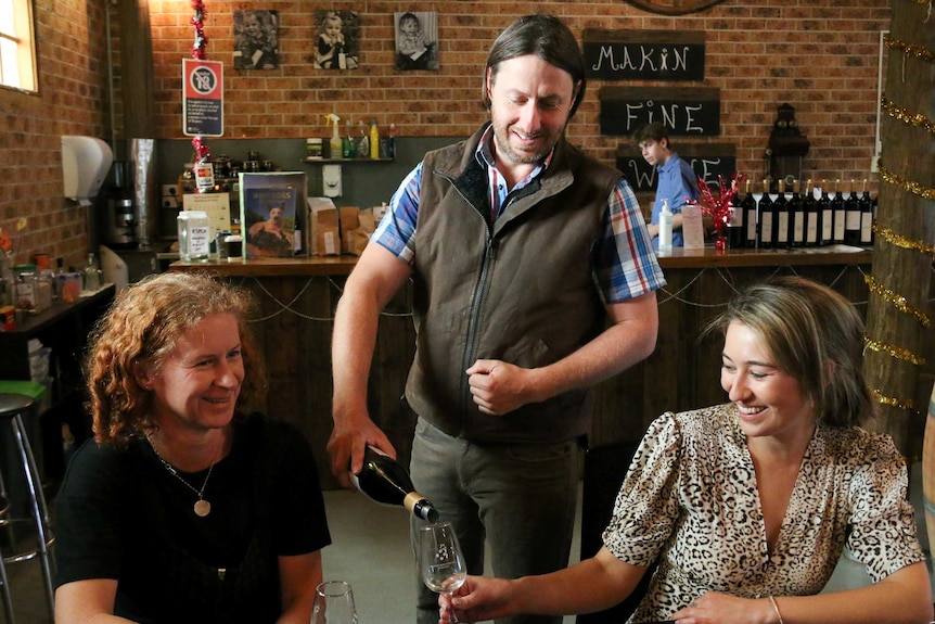 Man pouring a bottle of wine into glasses