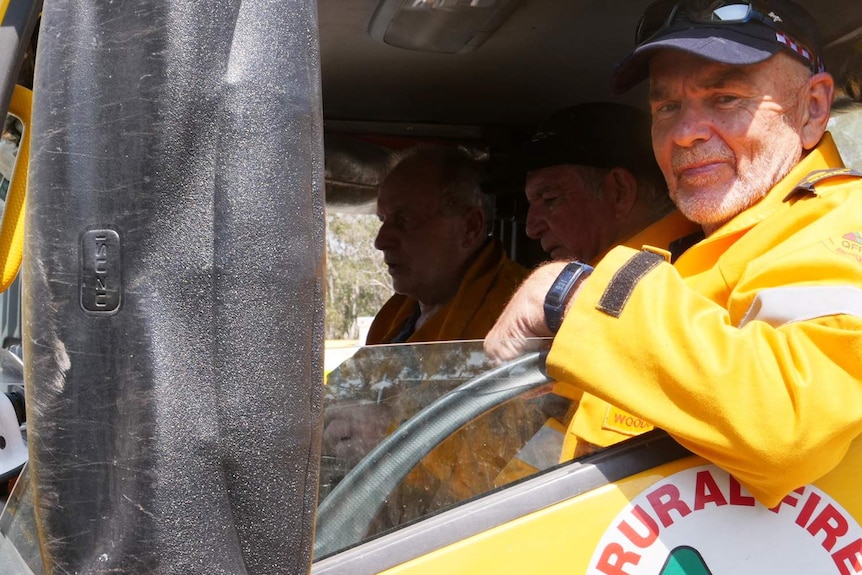 Woodgate volunteer firefighter John Foster smiles as he sits on the passenger side of a fire vehicle.