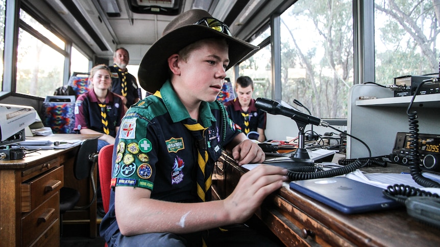 Austin Williams talking through a microphone from the inside of an old bus with other Castlemaine venturers looking on.