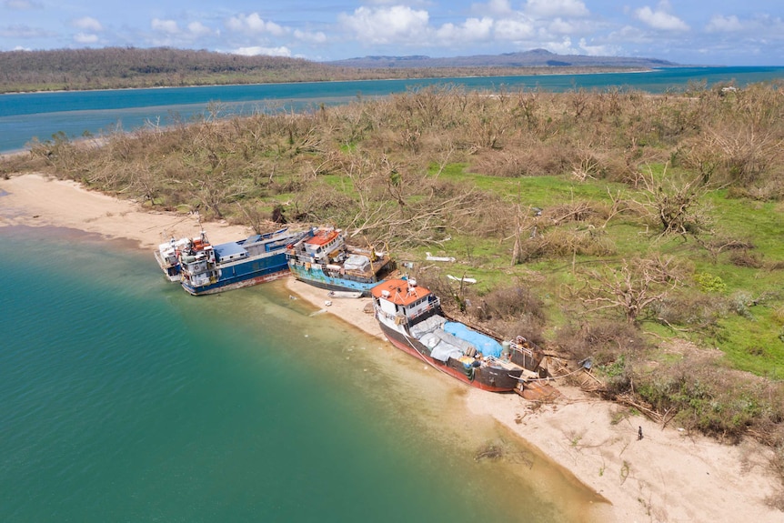 An aerial photo shows three ships pushed onto a low-lying island with its trees stripped of vegetation as a result of a cyclone.