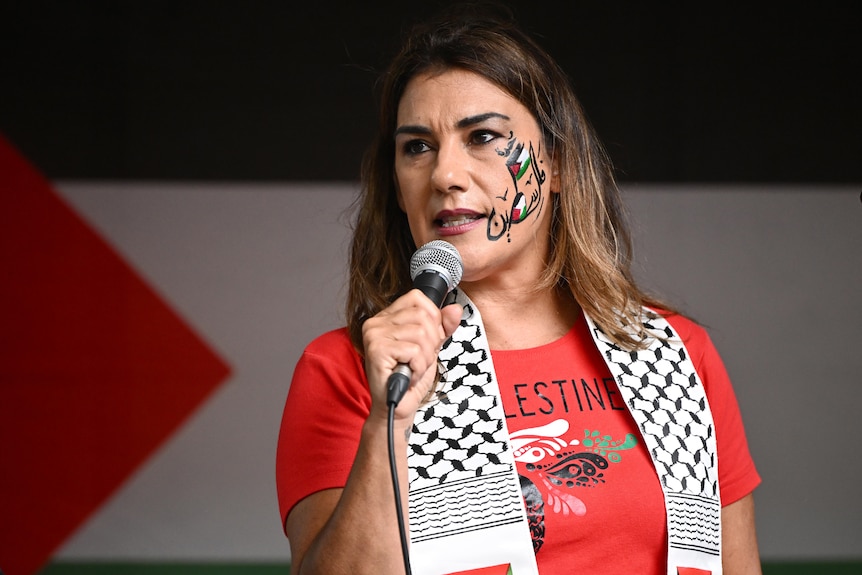 Independent Senator Lidia Thorpe speaks during a Free Palestine rally, with Palestinian flags painted on her face.