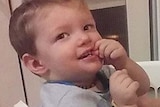 Toddler Mason Jet Lee looks up as he sits in a washing basket with another anonymous child.