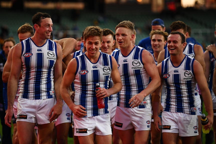 North Melbourne Kangaroos players smile as they walk off the field after their first win of the 2021 AFL season.