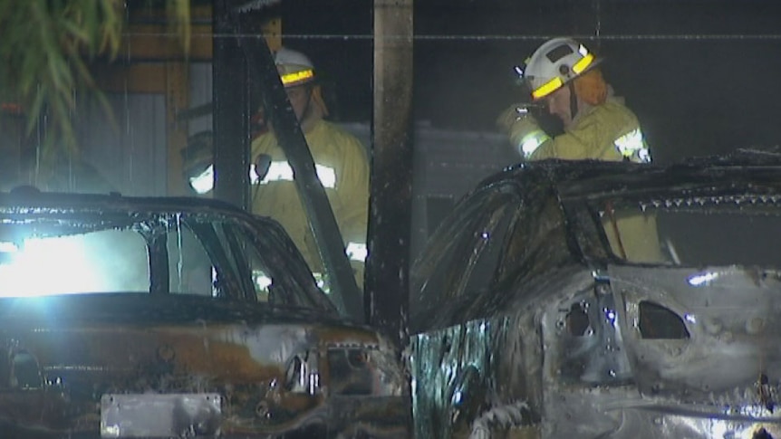 Firefighters inspect burnt-out cars after blaze at car storage facility at Archerfield