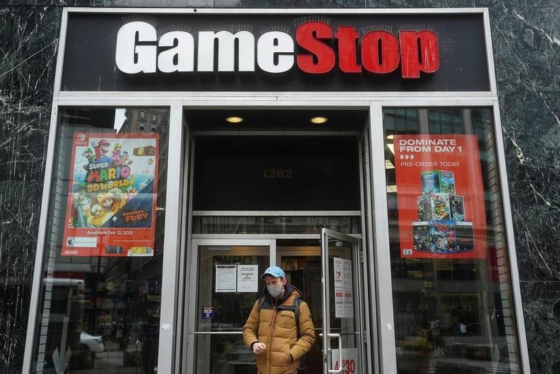 A man wearing a mask walks out of a GameStop store.