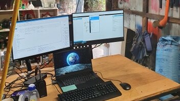 A desktop set-up inside someone's shed, with tools hanging on the wall.