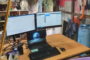 A desktop set-up inside someone's shed, with tools hanging on the wall.