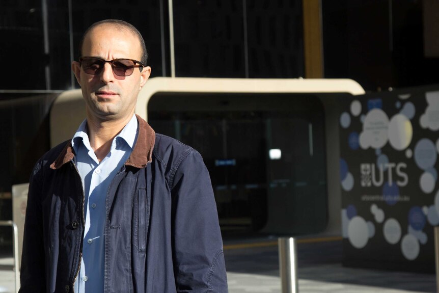 Lecturer Dr Kais Al-Momani standing in front of University of Technology building.