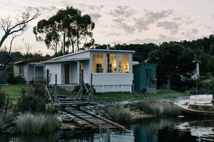 A boatshed lit up across the water