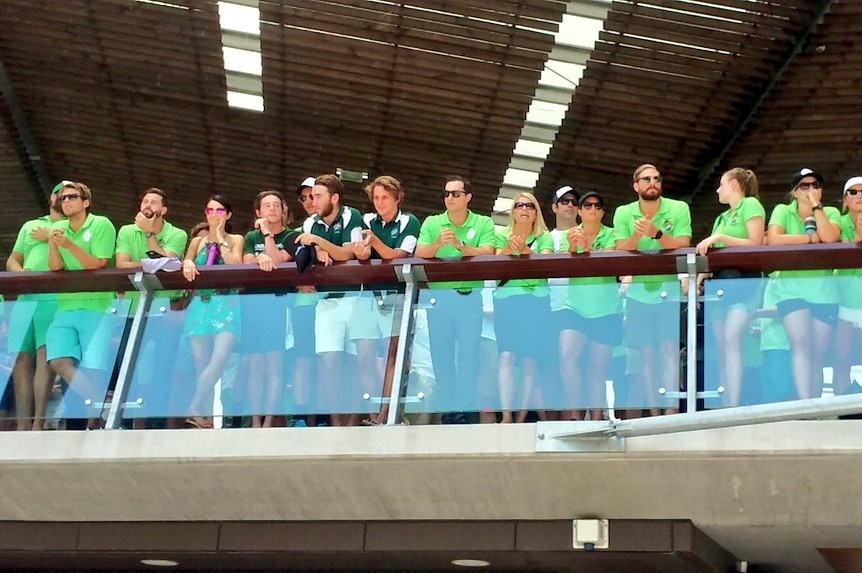 Members of Cole Miller's water polo team line a balcony, dressed in green.