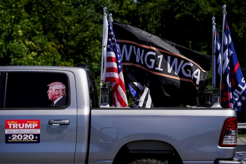 Pro-Trump flags and a flag reading WWG1WGA, a reference to the QAnon slogan is seen on a truck.