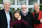 Members of The Seekers in present age smile and hug.