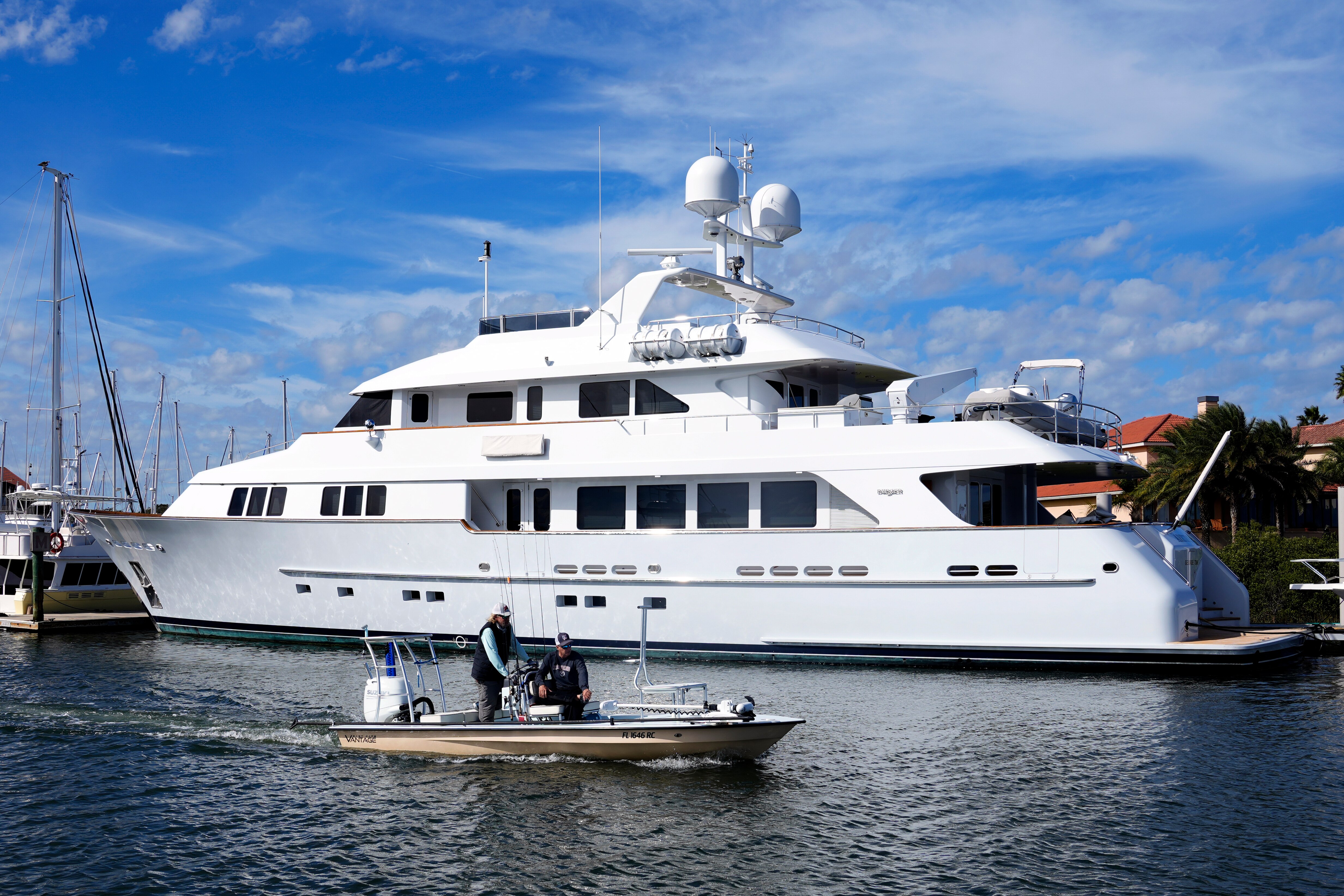 A  128-foot yacht sits docked in the harbour on a sunny day. 