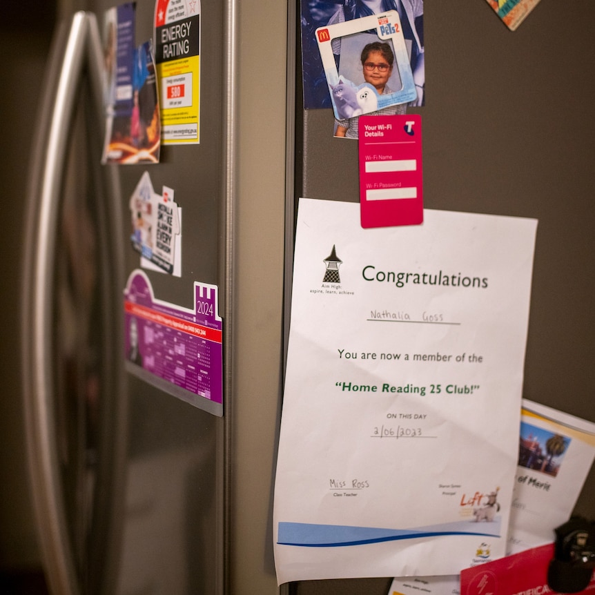 a childs certificate pinned to a fridge with a magnet. 