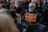 A man holds a sign reading Save Hobart City