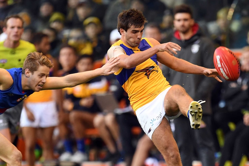 Andrew Gaff of the West Coast Eagles kicks a football chased by Lachie Hunter of the Western Bulldogs.