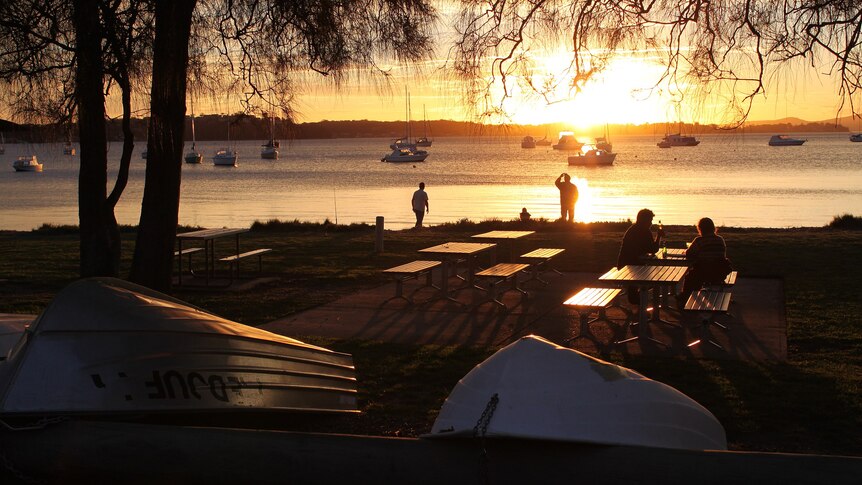 People enjoying beers during sunset near the beach.