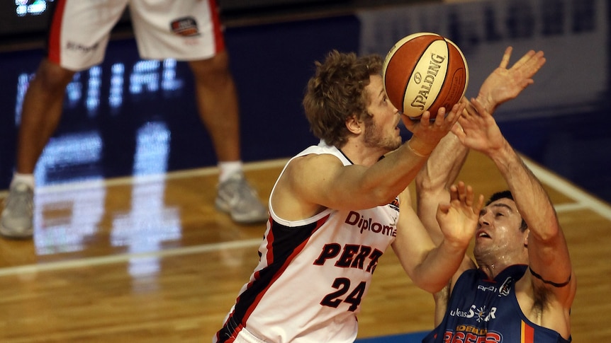 Big Cats ... Perth's Jesse Wagstaff shoots over Adelaide defender Greg Hire on his way to 22 points.