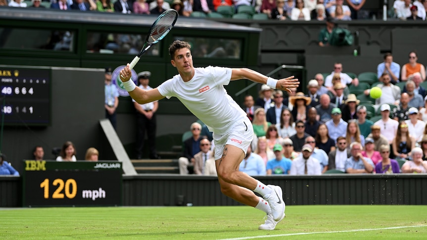An Australian tennis player brandishes his racquet, ready to hit a forehand as the ball comes toward him at Wimbledon. 