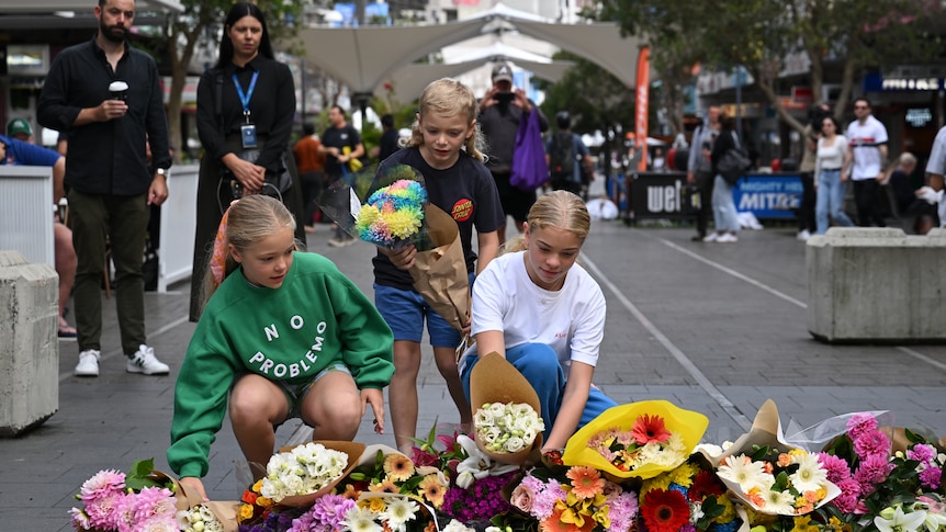 Three children lay flowers at Westfield Bondi Junction