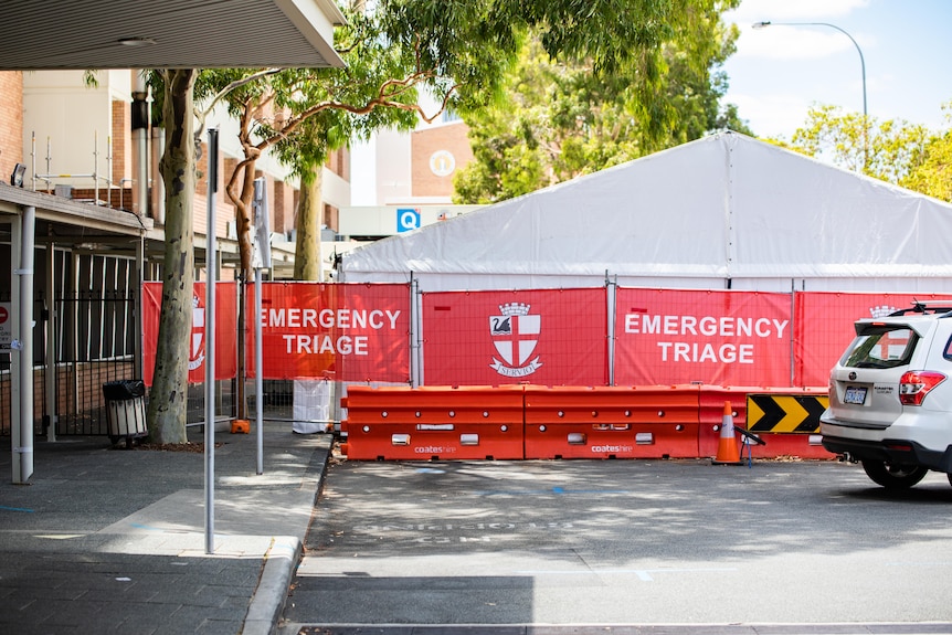 A tent behind a fence with a sign reading 'Emergency Triage'.