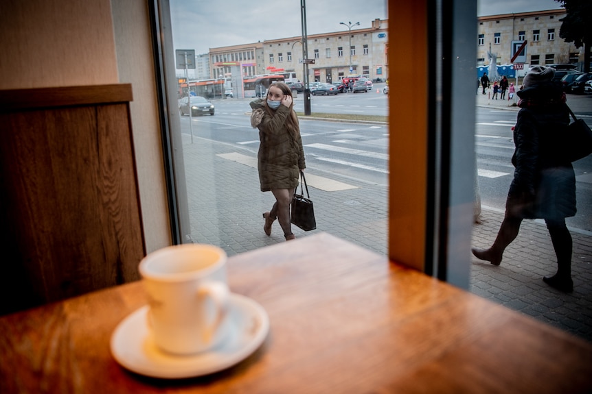 A woman walks past a cafe 