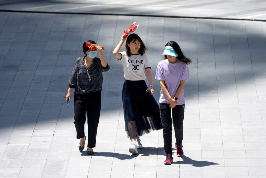 Three women walking together across a Beijing road