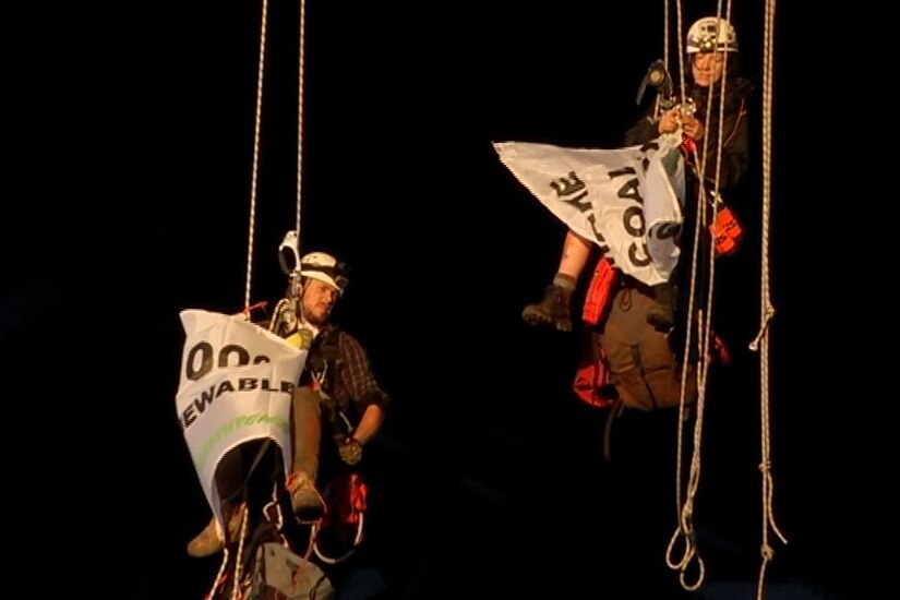 two climbers suspended from rope under a bridge