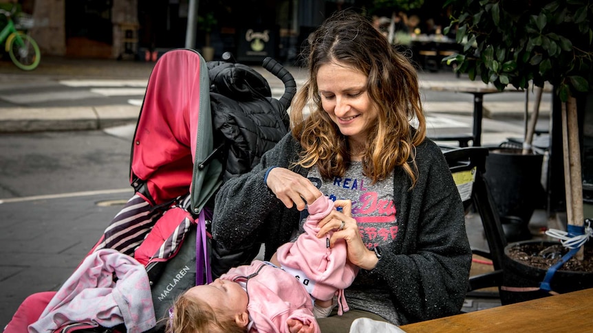 Giselle Haber changes her baby daughter Luna on a cafe table.