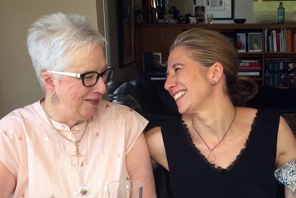 Two women laugh lovingly together.