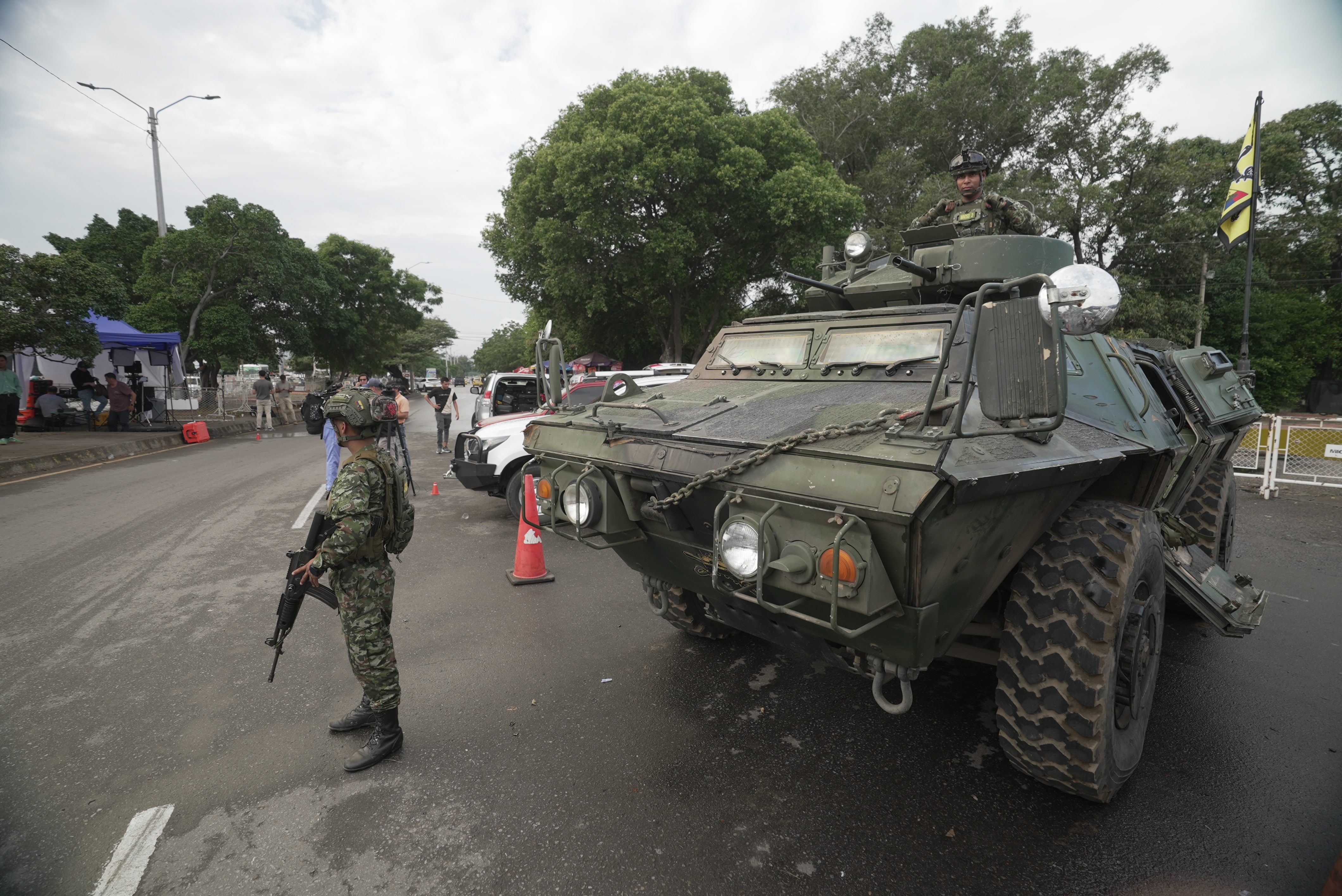 Um soldado parado na frente de um veículo blindado na estrada. 