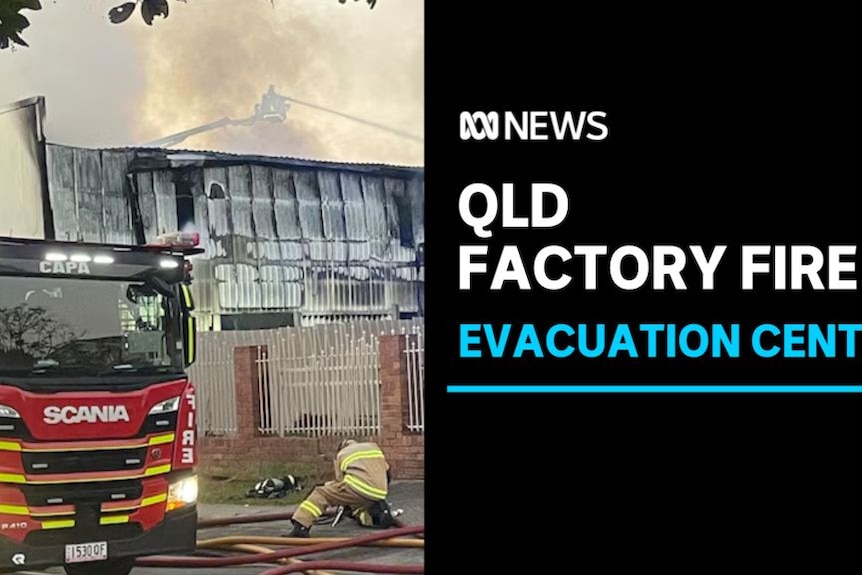 Qld Factory Fire, Evacuation Centre: A fire truck and firefighter in front of a heavily damaged, smoking building.
