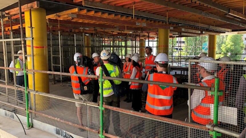 People in hard hats and bright safety vests in a part built building.