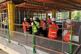 People in hard hats and bright safety vests in a part built building.