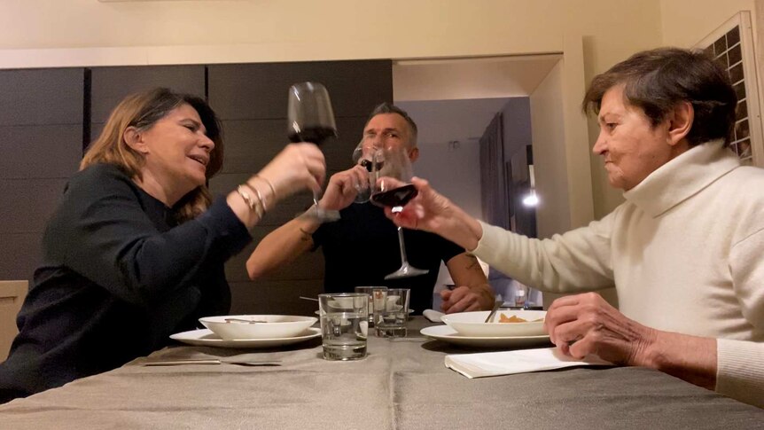 Emi, Maria and Ariel raise glasses over dinner.
