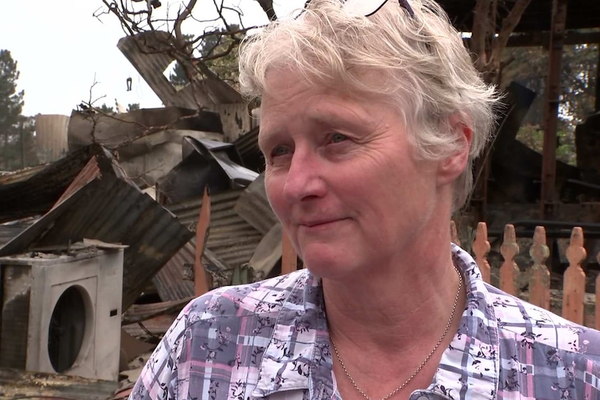 woman in front of a building destroyed by fire