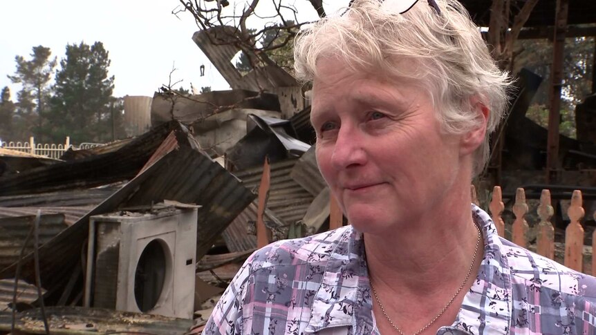 woman in front of a building destroyed by fire