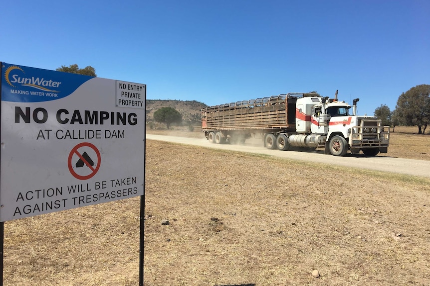 cattle truck on gravel road driving past no camping sign
