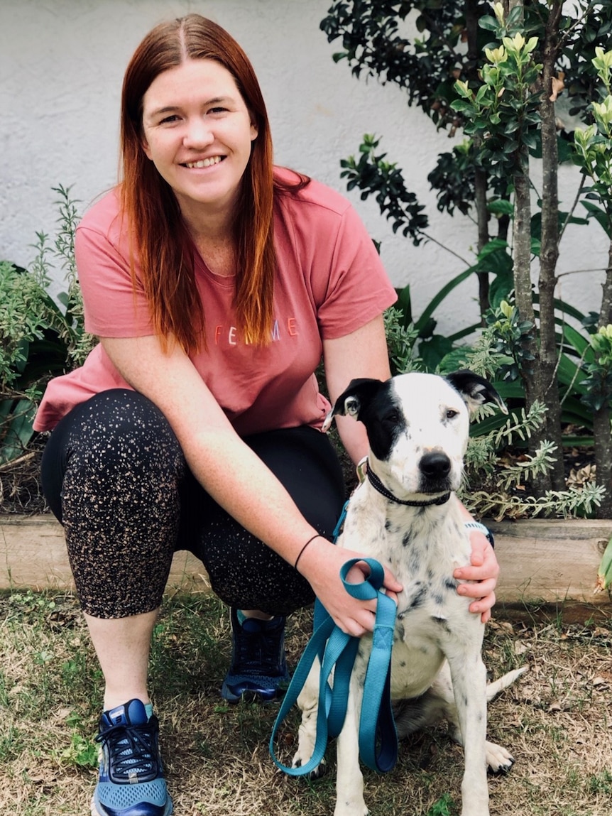 Lady kneeling with her foster dog Shelby.