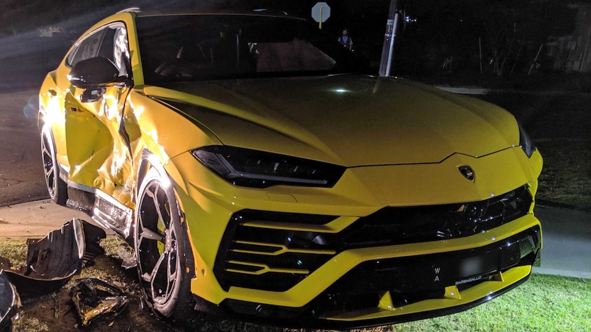 A smashed yellow Lamborghini SUV at night.