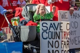 A baby holds up a protest sign.